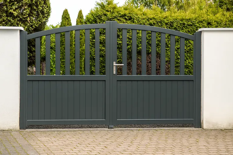 Portón doble de aluminio gris oscuro con cerramiento a juego, diseñado para fincas rurales y preparado para soportar condiciones exigentes