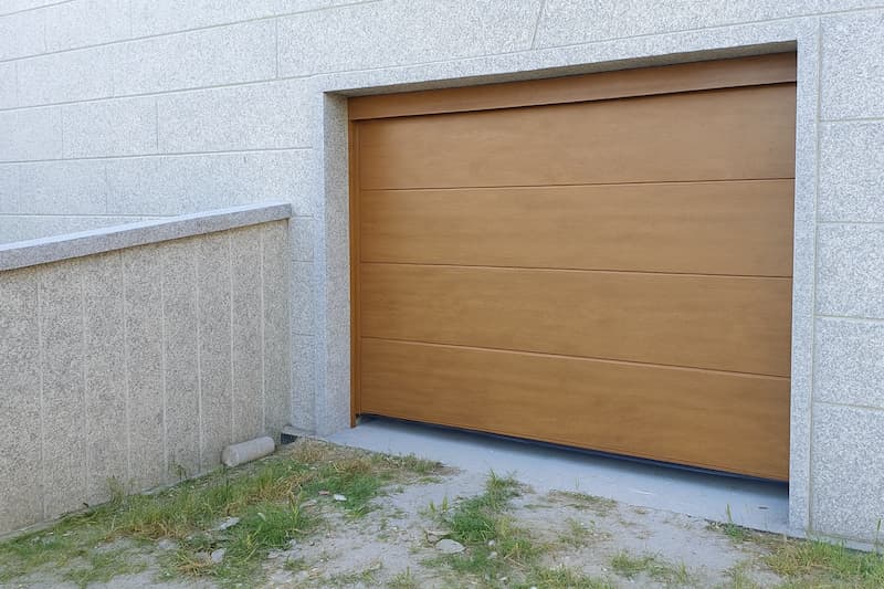 Imagen de una puerta de garaje seccional en color madera clara instalada en una vivienda unifamiliar en la urbanización Casas Novas de Pontevedra